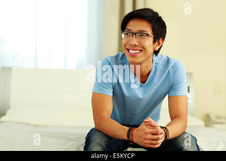 Happy asian man sitting on the bed at home Stock Photo