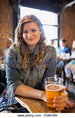 Portrait of smiling woman drinking beer in pub