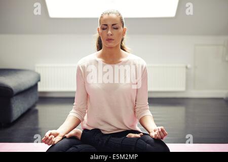 Portrait of beautiful woman exercise. Relaxing at home with yoga workout. Fit caucasian female model in meditation. Stock Photo