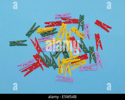 Close up of multicolored clothes peg shaped paper clips on a blue background. Stock Photo