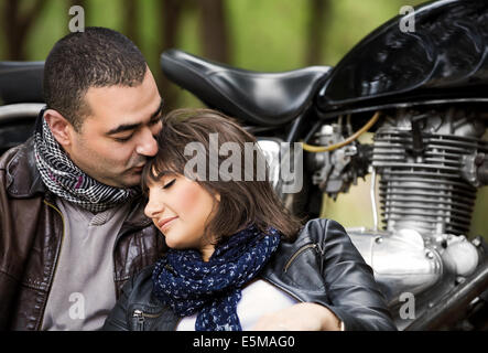 Attractive woman sleeping on shoulders of her husband, sitting near bike, relaxation after bikers tour in the forest Stock Photo