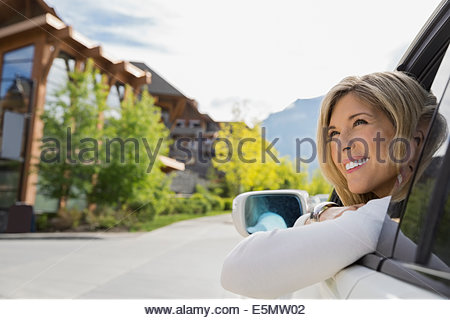 Smiling woman in car arriving at hotel