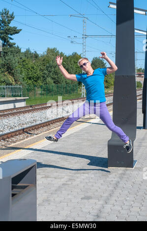 Handsome young guy jumping on train station Stock Photo