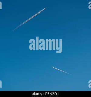 Two airplane contrails, travelling in opposite directions, in a perfectly blue summer sky; square format. Stock Photo