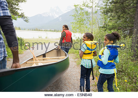 Family carrying canoe toward lake