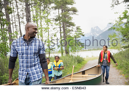 Family carrying canoe away from lake