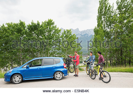 Men removing bicycles from bike rack on car
