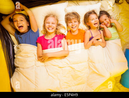 Five kids lay under blanket Stock Photo