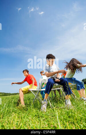 Kids playing game and sit fast on chairs outside Stock Photo