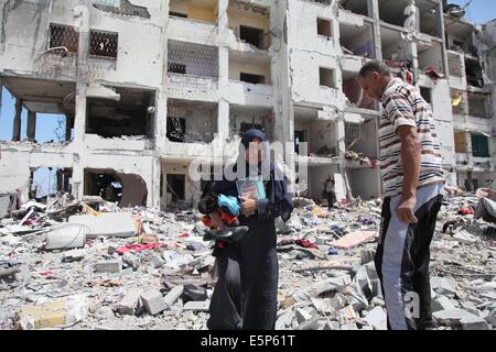 Gaza City, Gaza Strip, Palestinian Territory. 4th Aug, 2014. Palestinians walk in front of the rubble of buildings destroyed in Israeli strikes, in Beit Lahiya, northern Gaza Strip, Monday, Aug. 4, 2014 Credit:  Ezz Al-Zanoun/APA Images/ZUMA Wire/Alamy Live News Stock Photo