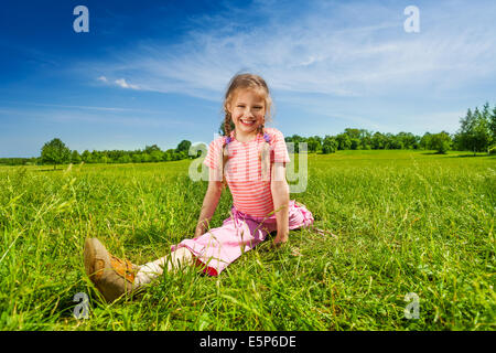 Girl stretching legs apart on grass Stock Photo