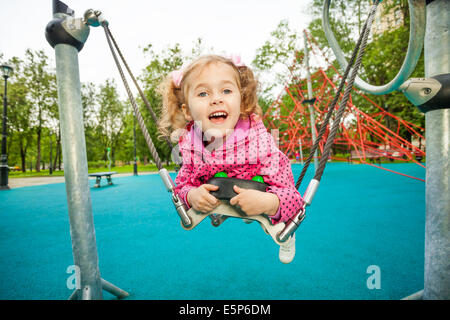 Laughing girl laying and swinging on swing set Stock Photo