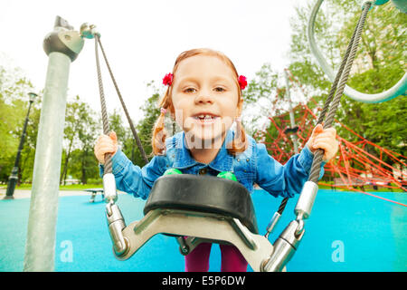 Funny girl portrait on swing set of playground Stock Photo