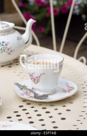 Afternoon tea served in vintage floral cups and saucers on a garden table Stock Photo