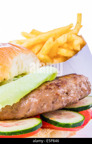 burger in bun with french fries and cucumber and tomato salad isolated in closeup Stock Photo