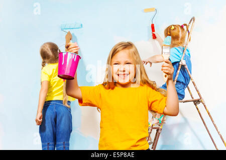 Three little girls painting the wall Stock Photo