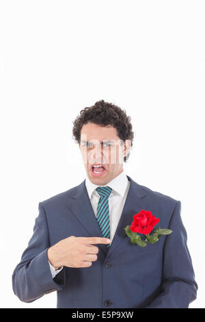 adult man in suit with disgust face expression showing with his hand rose flower which is in his jacket pocket Stock Photo