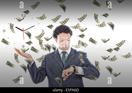 Businessman looking at his watch with money rain around him, rich man in suit measuring time on clock surrounded by flying dolla Stock Photo