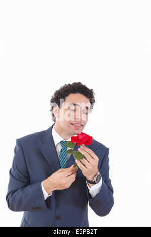 handsome man seducer in a business suit with weird geeky face expression holding rose in his hand and smelling it, isolated on w Stock Photo