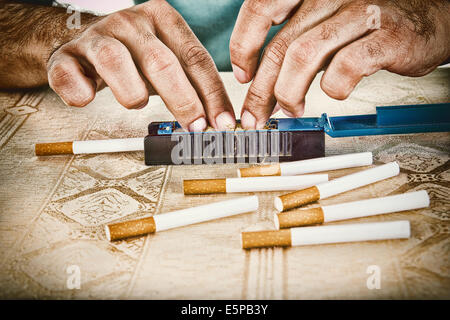 Male hands making cigars with rollings filled with tobacco to satisfy his habit and to smoke handmade cigarettes Stock Photo
