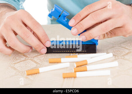 Preparing handmade cigarettes using rollings and tobacco to fill sticky paper and filter and satisfy habits Stock Photo