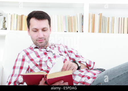 young casual man reading a book relaxing on sofa in horizontal style Stock Photo