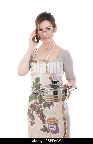 Front view portrait of young smiling caucasian woman dressed in apron holding saucepan and talking on the phone isolated on whit Stock Photo