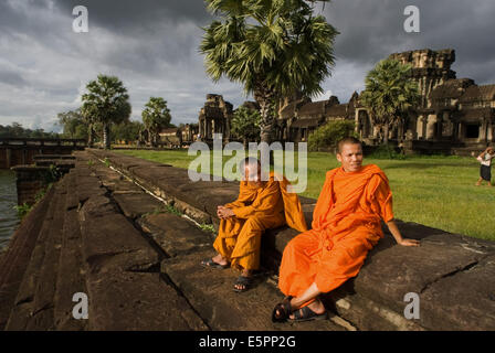 Two Buddhist monks on the outside of the Temple of Angkor Wat. Angkor Wat, in its beauty and state of preservation, is unrivaled Stock Photo