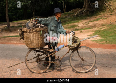 A man goes to fetch firewood with a bicycle near the gateway to Angkor Thom. Angkor Thom is undeniably an expression of the high Stock Photo