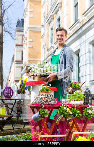 Young handsome florist delivering palette of flowers or viola Stock Photo