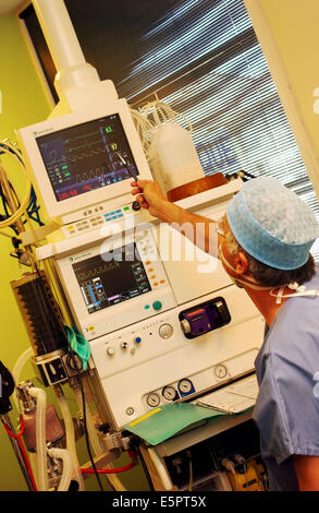 Anaesthetist in surgical dress beside anaesthetic monitoring equipment during surgery. Stock Photo