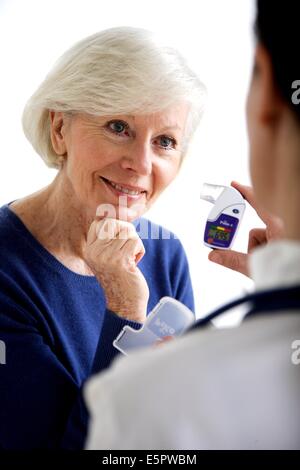 Doctor explaining a female patient the use of a PIKO-6, a digital peak flow meter. Stock Photo