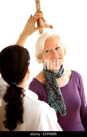 Doctor measuring the height of a female patient during medical consultation. Stock Photo