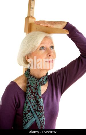 Elderly woman measuring herself with height gauge. Stock Photo