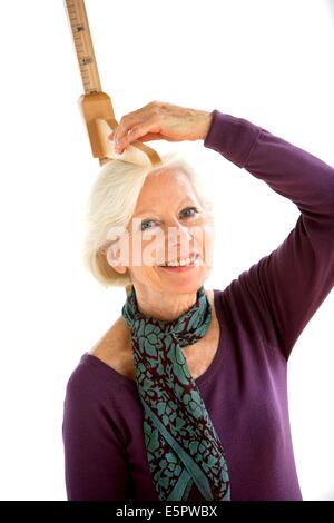 Elderly woman measuring herself with height gauge. Stock Photo