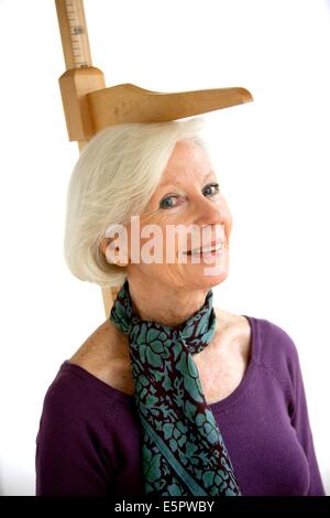 Elderly woman measuring herself with height gauge. Stock Photo