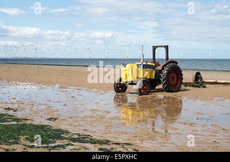 A tractor, used to launch fishing boats, on Redcar beach with offshore wind farm behind, Redcar and Cleveland, England, UK Stock Photo