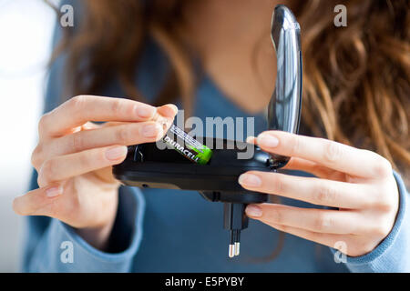 Woman using charger for rechargeable batteries. Stock Photo