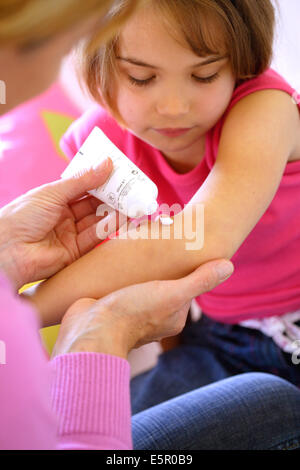 Woman applying pomade on girl's arm. Stock Photo