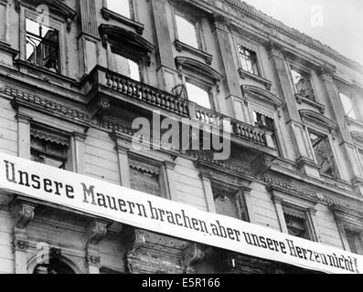 The propaganda photo from a Nazi news report shows a banner reading 'Our walls are broken, but not our hearts' on a destroyed department store in Berlin, Germany, April 1944. The original Nazi propaganda text on the back of the picture reads: 'Our walls are broken, but not our hearts! With these and similar banners, which were attached to buildings that were destroyed by the senseless enemy rage, the population of the city of Berlin at the front greeted the Fuhrer on his 55th birthday: These mottos expressed the indomitable struggle and will to win, which cannot be broken by hostile terror.' P Stock Photo