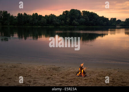 Bonfire on the bank of the river at sunset time Stock Photo