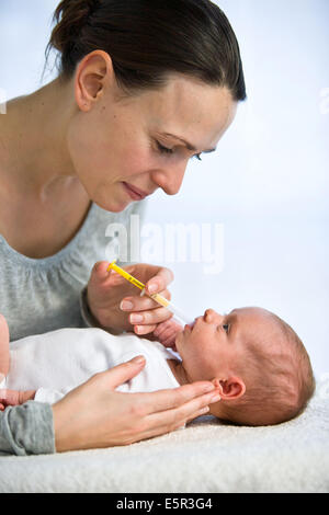 Mother giving her one month old baby vitamin D with a pipette. Stock Photo