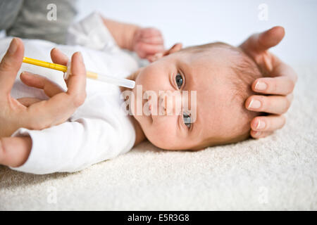 Mother giving her one month old baby vitamin D with a pipette. Stock Photo