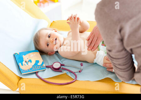 A doctor examines the abdomen of a 14-month-old baby palpating his belly. Stock Photo