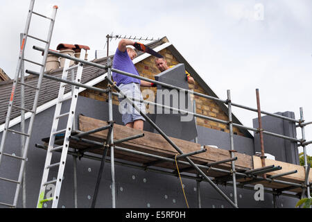 Builders attaching / fitting rigid foam wall insulation sheets / panels / boards to the gable end of Victorian terraced house UK Stock Photo