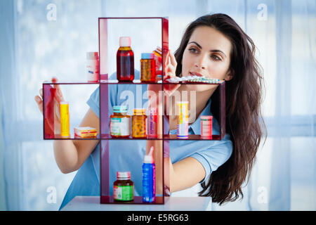 Woman taking medication in a medicine cabinet. Stock Photo