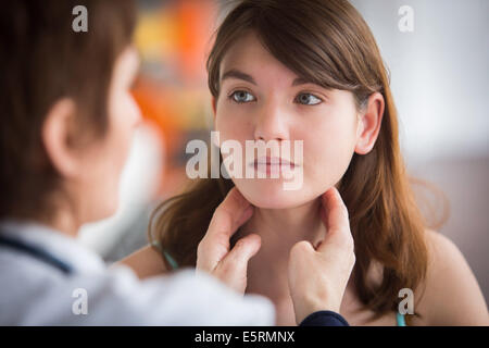 General practitioner palpating the lymphatic glands of a patient during medical consultation. Stock Photo