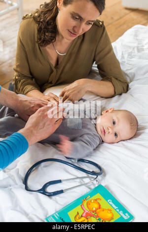 Doctor palpating the abdomen of a 5-month-old baby boy. Stock Photo