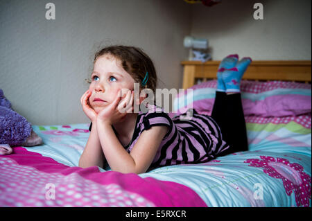 8, 9, 10 year old Girl looking thoughtful or bored on bed Stock Photo