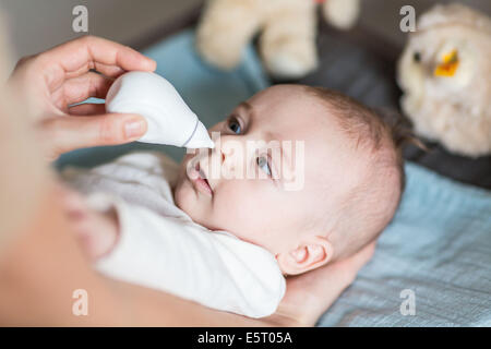 4 months old baby boy having his nose cleared with a nose-blower. Stock Photo